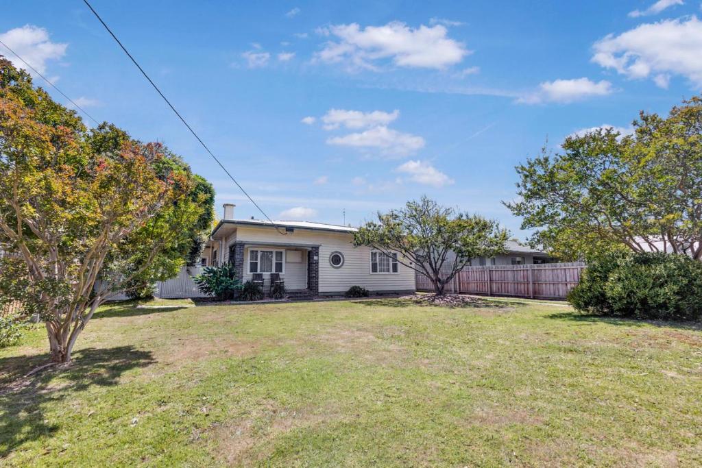 a white house with a fence in a yard at Cearc House in Bairnsdale