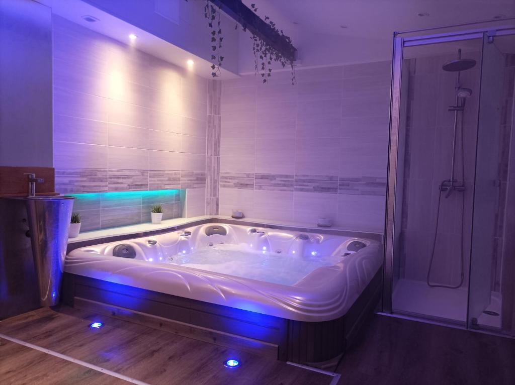 uma grande banheira com luzes azuis na casa de banho em A l'ombre du lilas em Épinal
