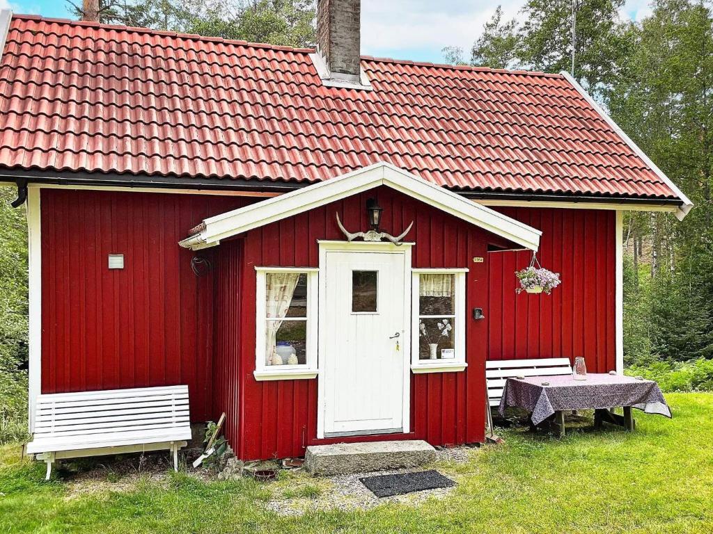 un cobertizo rojo con una puerta blanca y dos bancos en Holiday home HALDEN II, en Halden