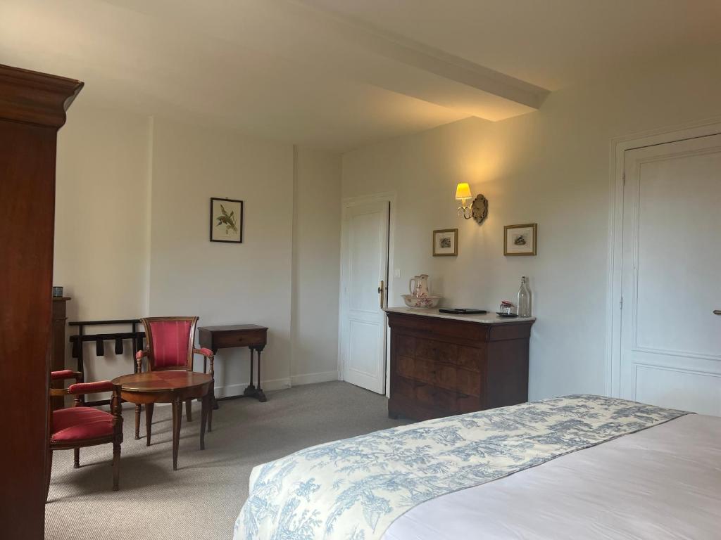 a bedroom with a bed and a desk and chairs at Manoir du Bois Mignon in Le Fleix