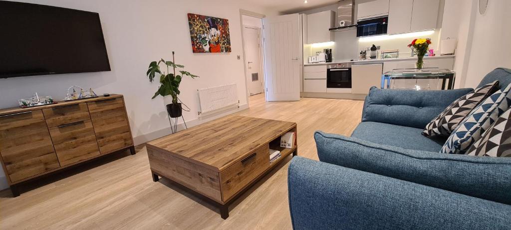 a living room with a blue couch and a tv at Luxury 1 Bedroom Waterside Apartment in Gloucester Docks in Gloucester