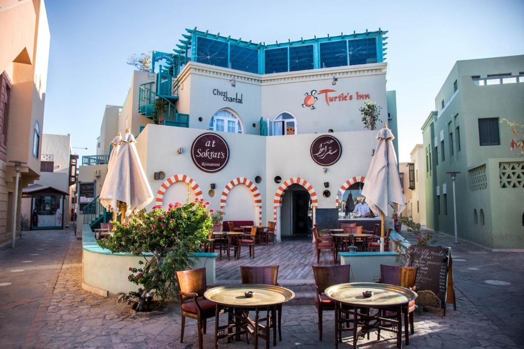 a restaurant with tables and chairs in front of a building at Turtle's Inn Hotel in Hurghada