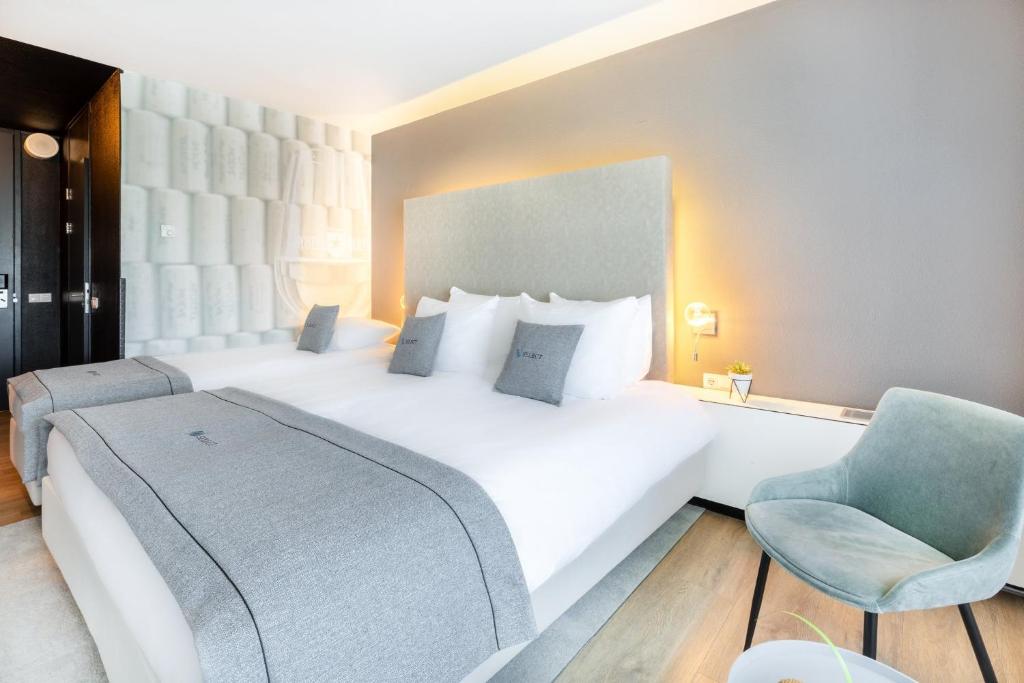 a bedroom with a large white bed and a chair at Select Hotel Maastricht in Maastricht