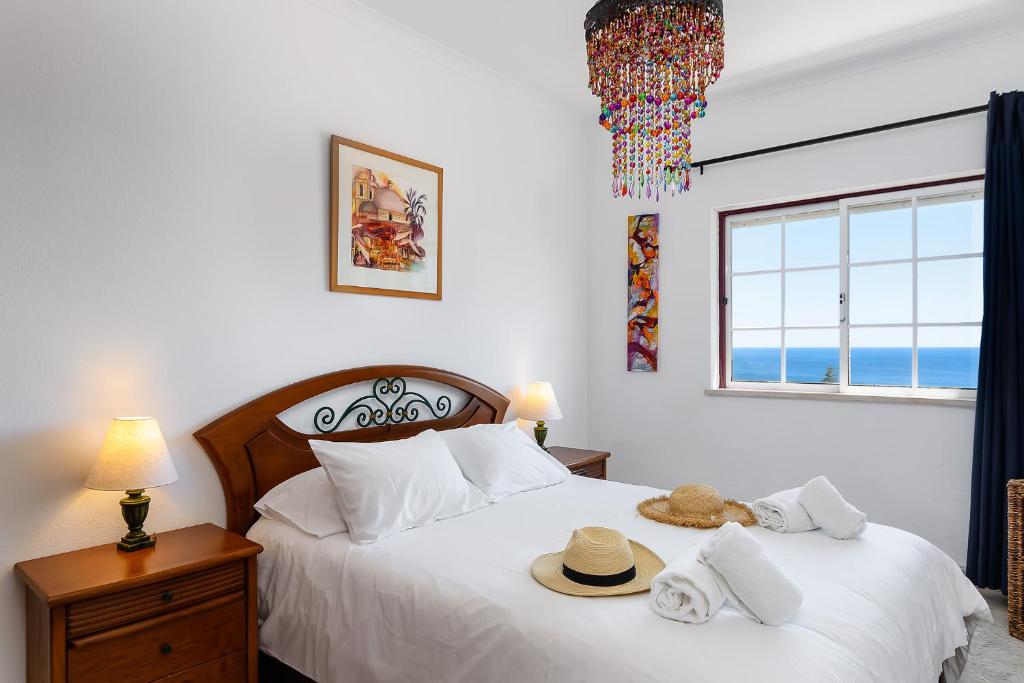 - une chambre avec 2 lits avec chapeaux et une fenêtre dans l'établissement Top Floor Ocean View Apartment – Near Beach Luz, à Luz