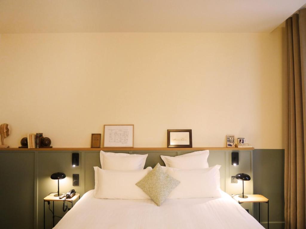 um quarto com uma cama com lençóis brancos e almofadas em Globe Et Cecil em Lyon