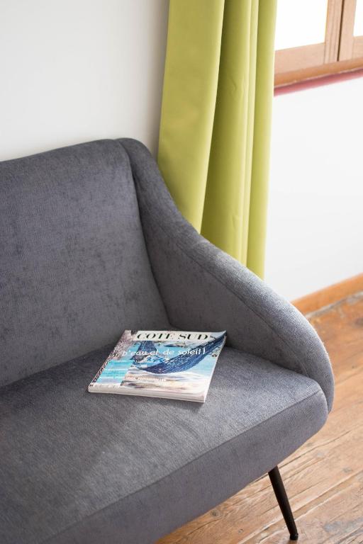 a magazine sitting on top of a gray couch at Ateliers, Terrasse - Parking - Clim in Arles