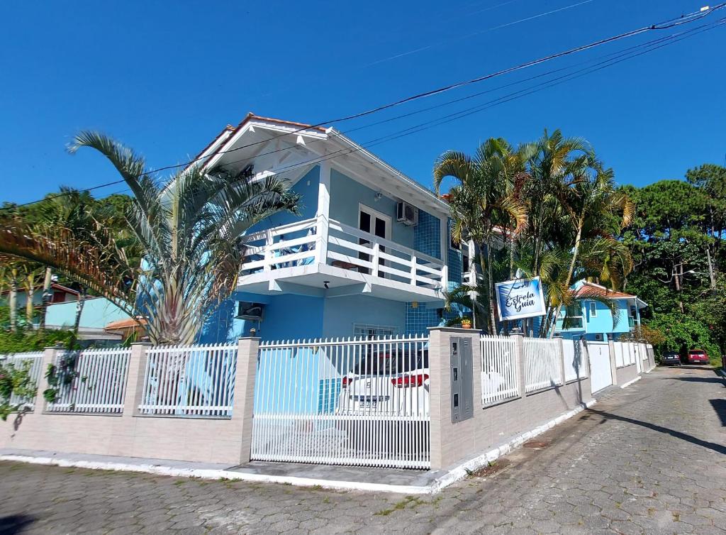 una casa azul con una valla blanca y palmeras en Pousada Estrela Guia, en Florianópolis