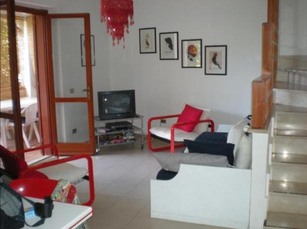 uma sala de estar com cadeiras vermelhas e uma televisão em Casa Indipendente Praialonga em Le Castella