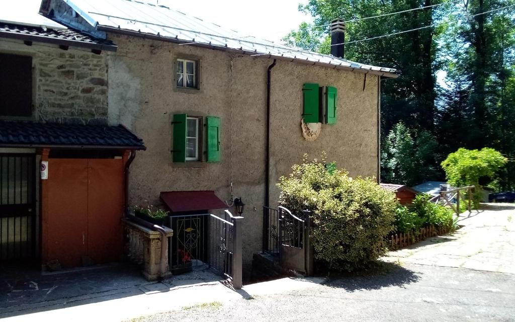 una casa con persianas verdes y una puerta en Baita 7 Nani en Pievepelago