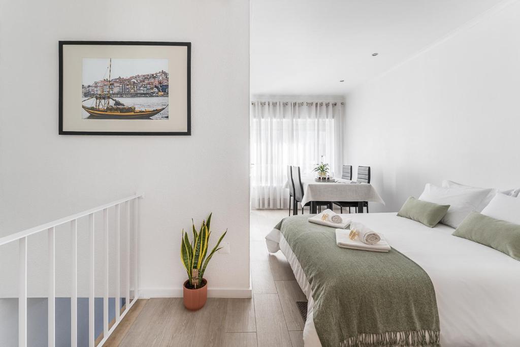 a white bedroom with a bed and a table at Casa Trindade in Porto