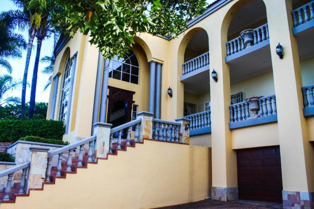 una casa amarilla con escaleras y palmeras en TDM's Boutique Guest House en Pretoria