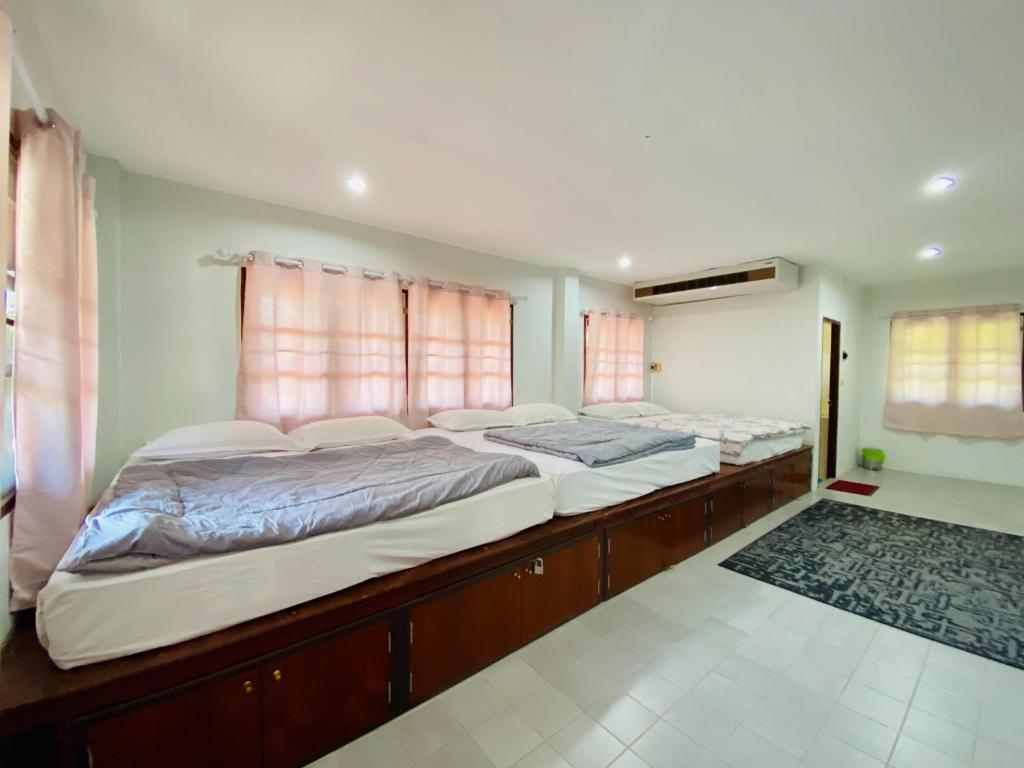 two beds in a room with two windows at Ma Baan House by the sea in Cha Am Beach