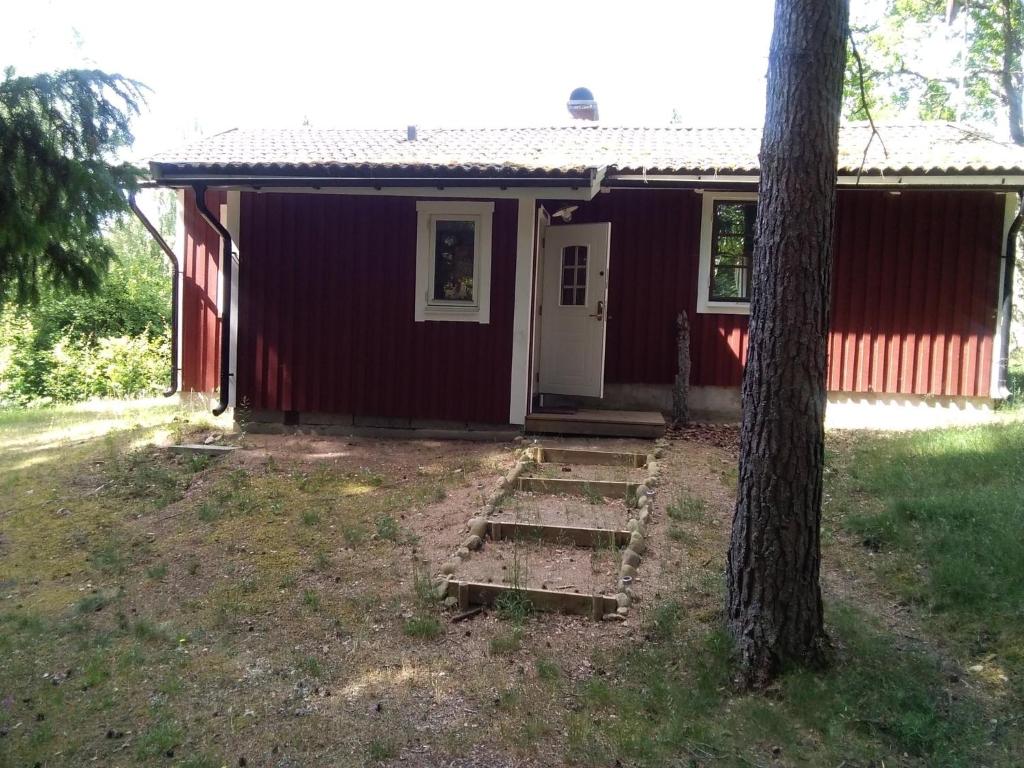 uma casa vermelha com um alpendre e uma árvore em Björktorpet em Linneryd