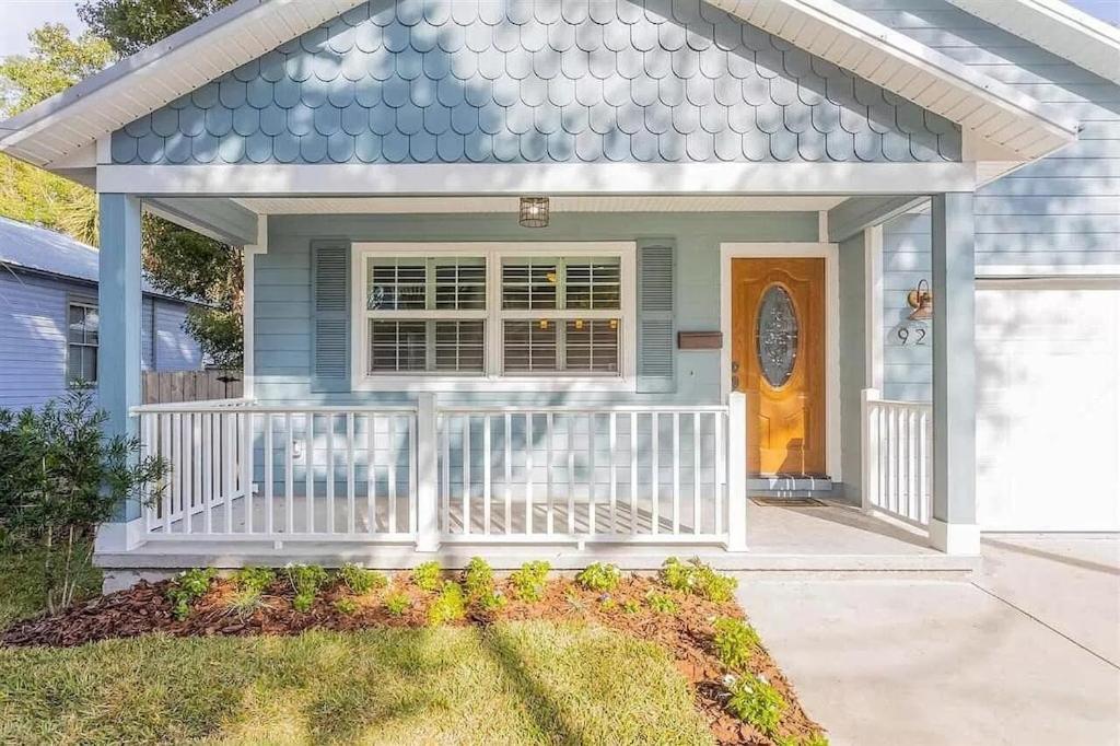 a house with a white porch and a door at Modern, Upscale, and New Blue Bungalow in the heart of Downtown St Augustine in St. Augustine