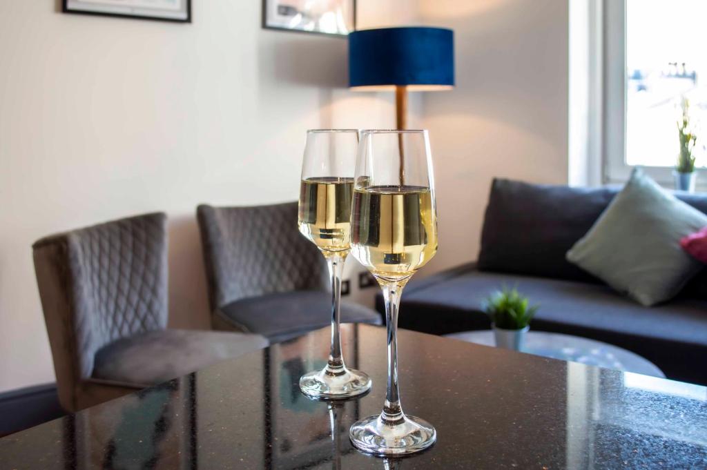 due bicchieri di vino bianco seduti su un tavolo di Kensington - Lexham Gardens by Viridian Apartments a Londra