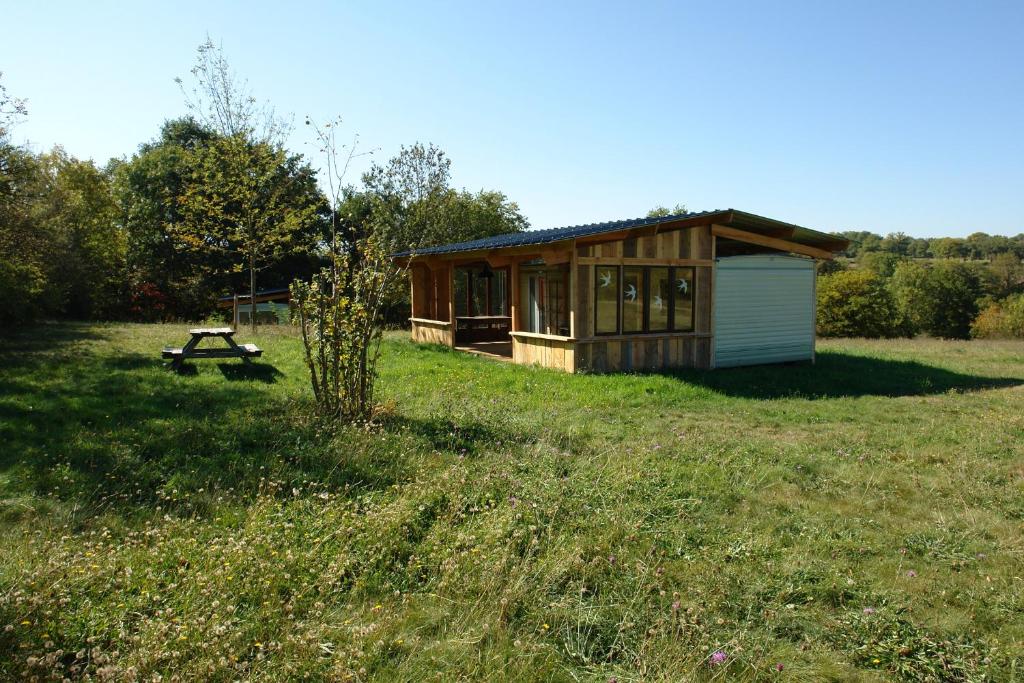 Mobile Home auf Campingplatz mit Naturbadesee في Parsac: كابينة صغيرة في حقل مع طاولة نزهة