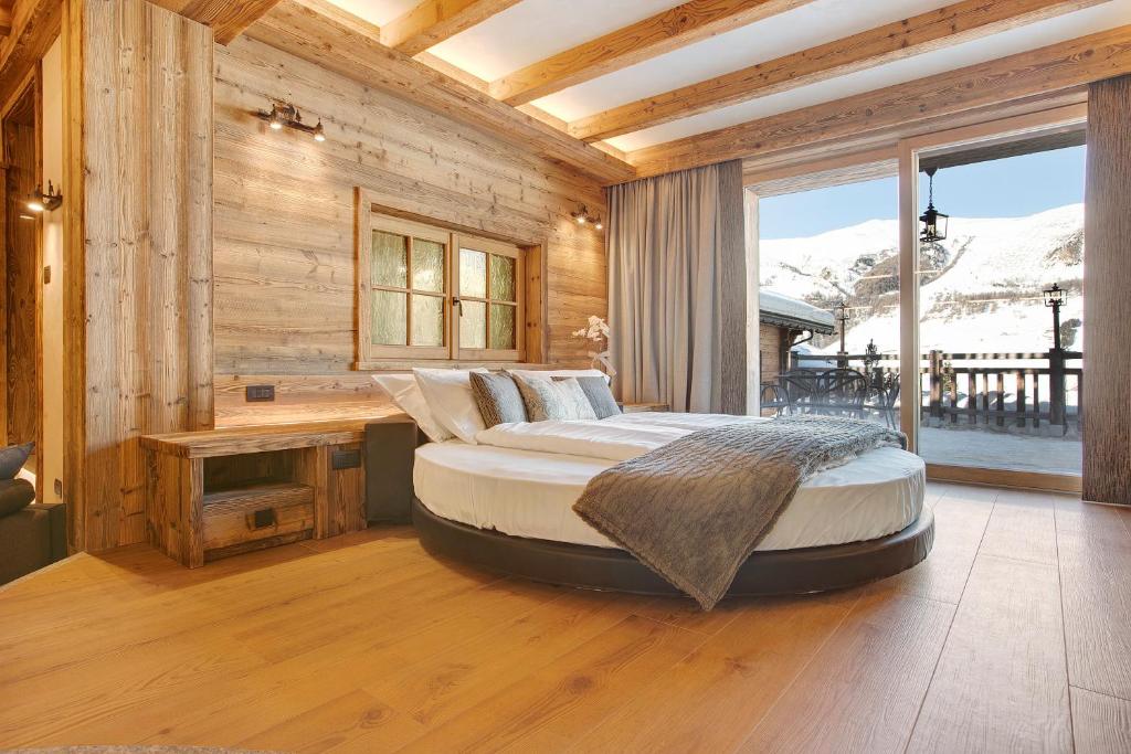 a bedroom with a large bed in a room with wooden walls at Le Chalet Suite in Livigno