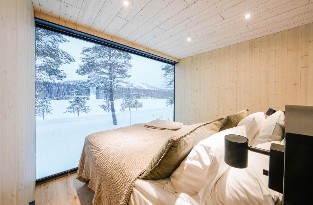 een slaapkamer met een bed en een groot raam bij Kuuru Lakeside in Salla