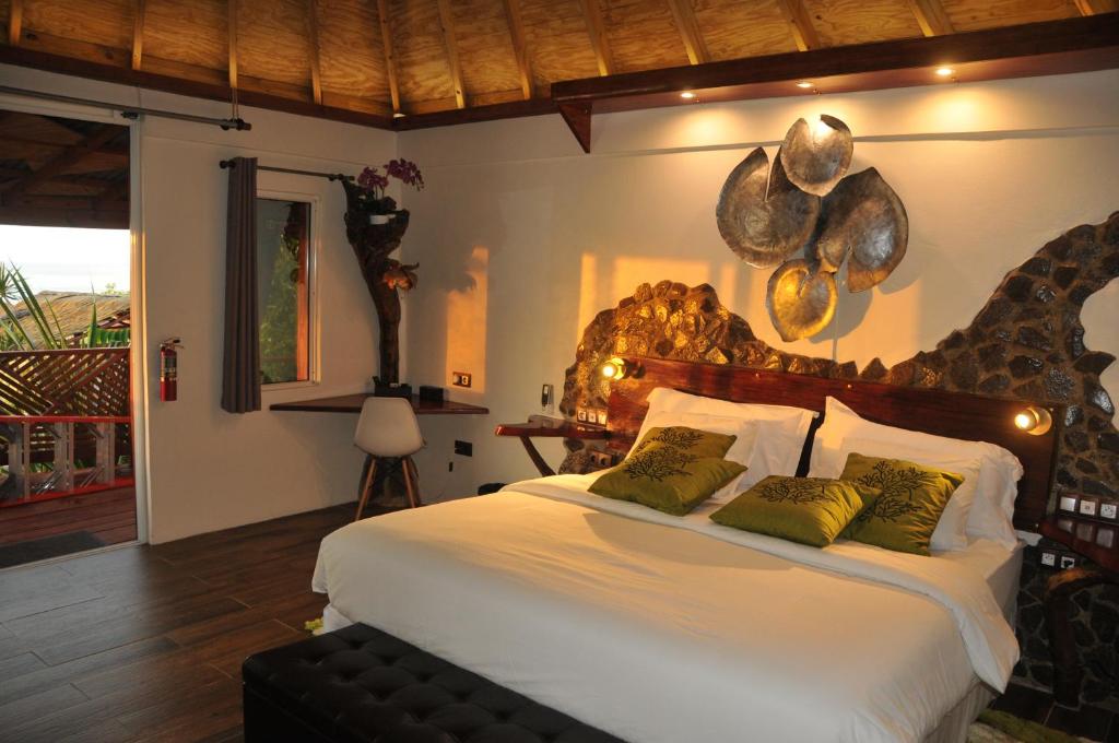 a bedroom with a large white bed with green pillows at Mango Island Lodges in Saint Joseph