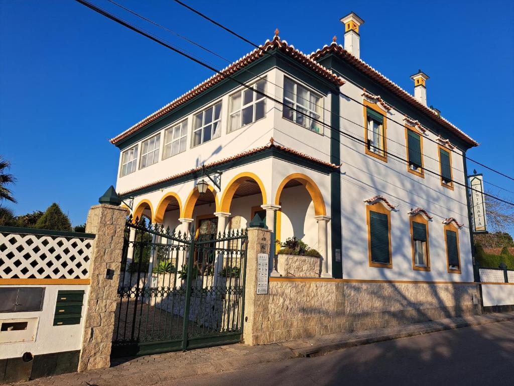 a large white house with a gate at Centenária in Oiã