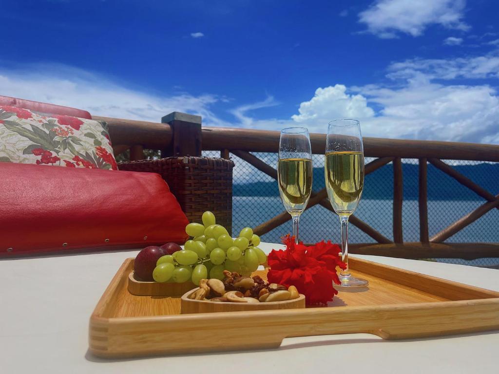2 Gläser Wein und ein Tablett mit Obst auf dem Balkon in der Unterkunft Mooi Guest House in Ilhabela