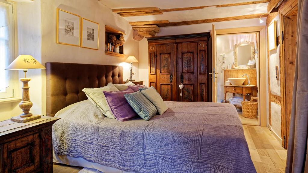 a bedroom with a bed with purple blankets and pillows at Remparts de Riquewihr - Le Petit Loup in Riquewihr