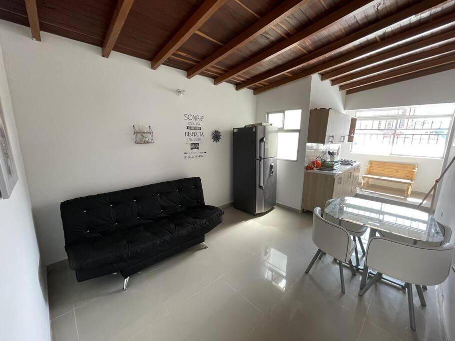 sala de estar con sofá negro y mesa en Aparta-hotel laureles 401, en Medellín