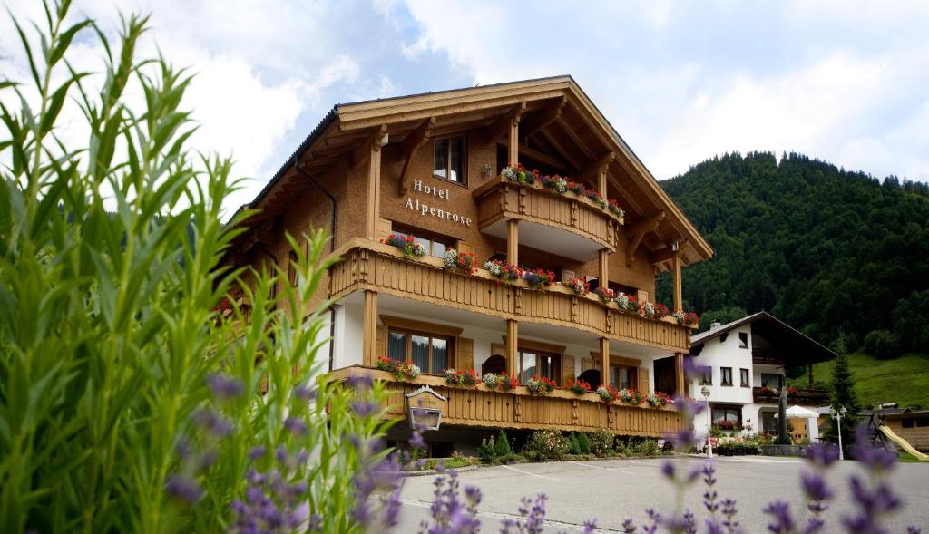 a building with a balcony with flowers on it at Hotel Alpenrose in Au im Bregenzerwald