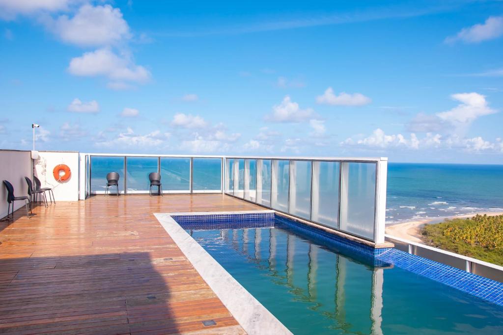 a balcony with a swimming pool and the ocean at Paiva Home Stay - Vista dos Sonhos in Recife