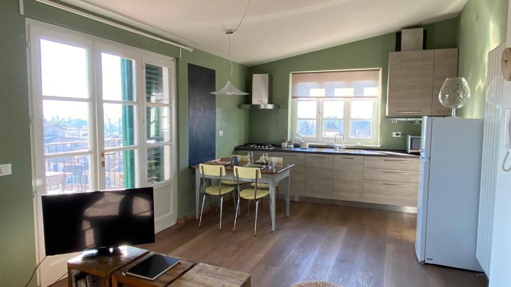 a kitchen with green walls and a table and a refrigerator at LuccaStay in Lucca