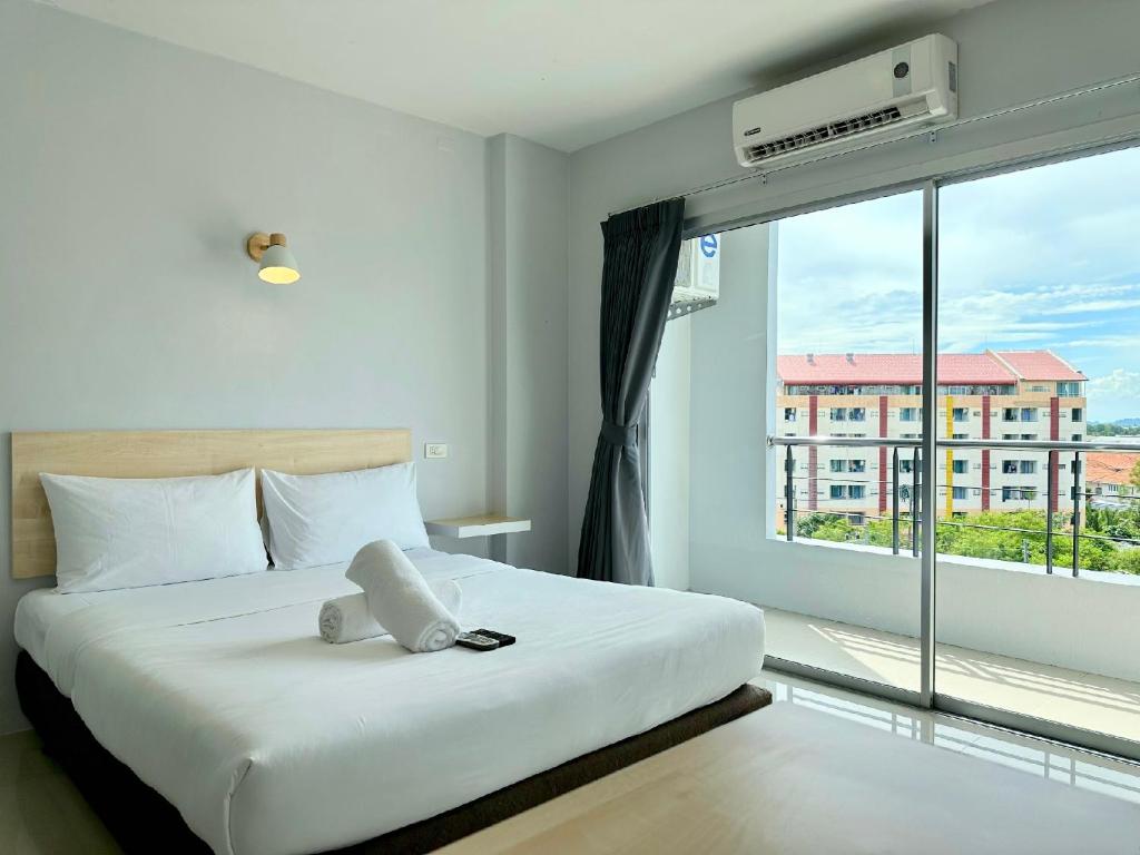 - une chambre avec un lit et une grande fenêtre dans l'établissement Sun Inn, à Songkhla