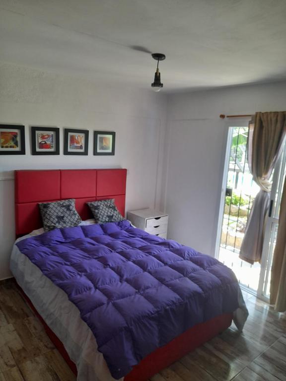 a bedroom with a purple bed with a red headboard at El Chañar in Villa Carlos Paz