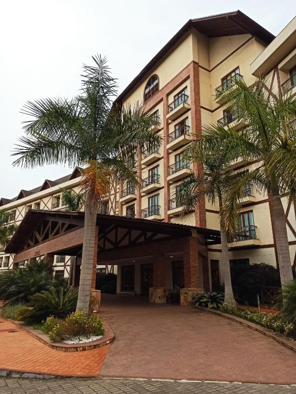 a building with palm trees in front of it at Flat Pedra Azul in Aracê