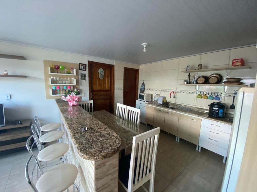 a kitchen with a counter with chairs and a counter top at Casa na praia de Itajuba in Barra Velha