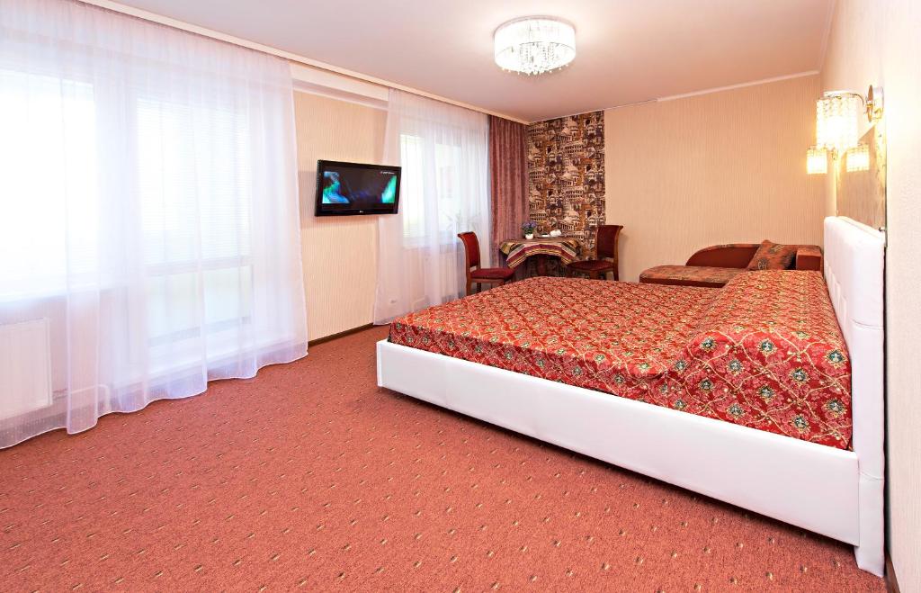 Habitación de hotel con cama y TV en Globus Hotel, en Perm