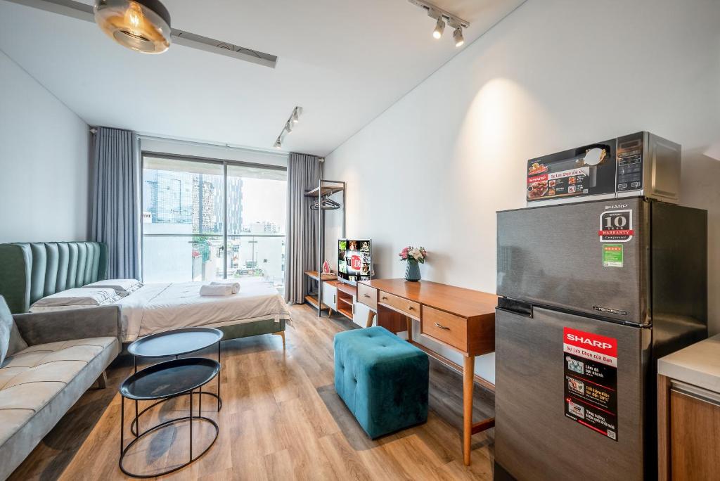 een woonkamer met een bank, een bureau en een koelkast bij Masteri Millennium-Bitexco view-Ivyhouse in Ho Chi Minh-stad