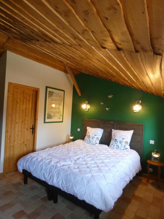 a bedroom with a large bed with a green wall at O 4 SAISONS DE BREILBON in Germond