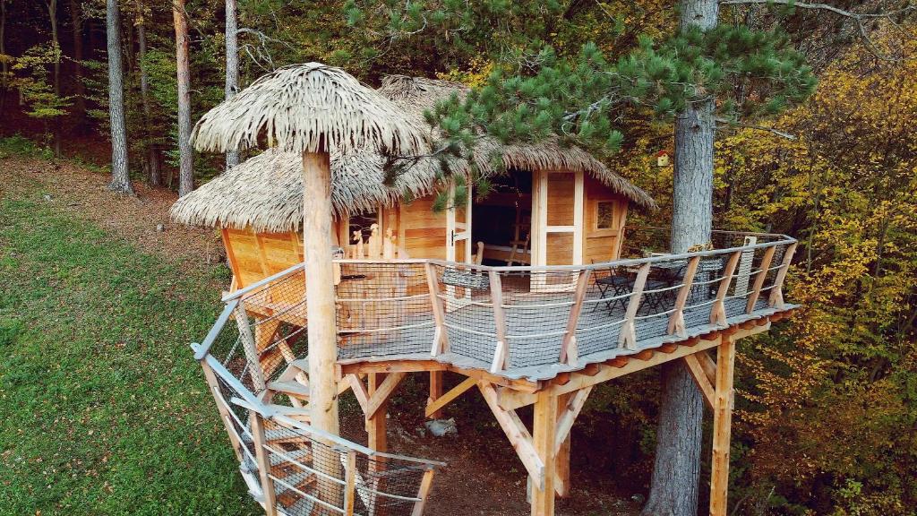 ein Baumhaus in einem Wald mit Strohdach in der Unterkunft Pine Point in Trenčianske Teplice