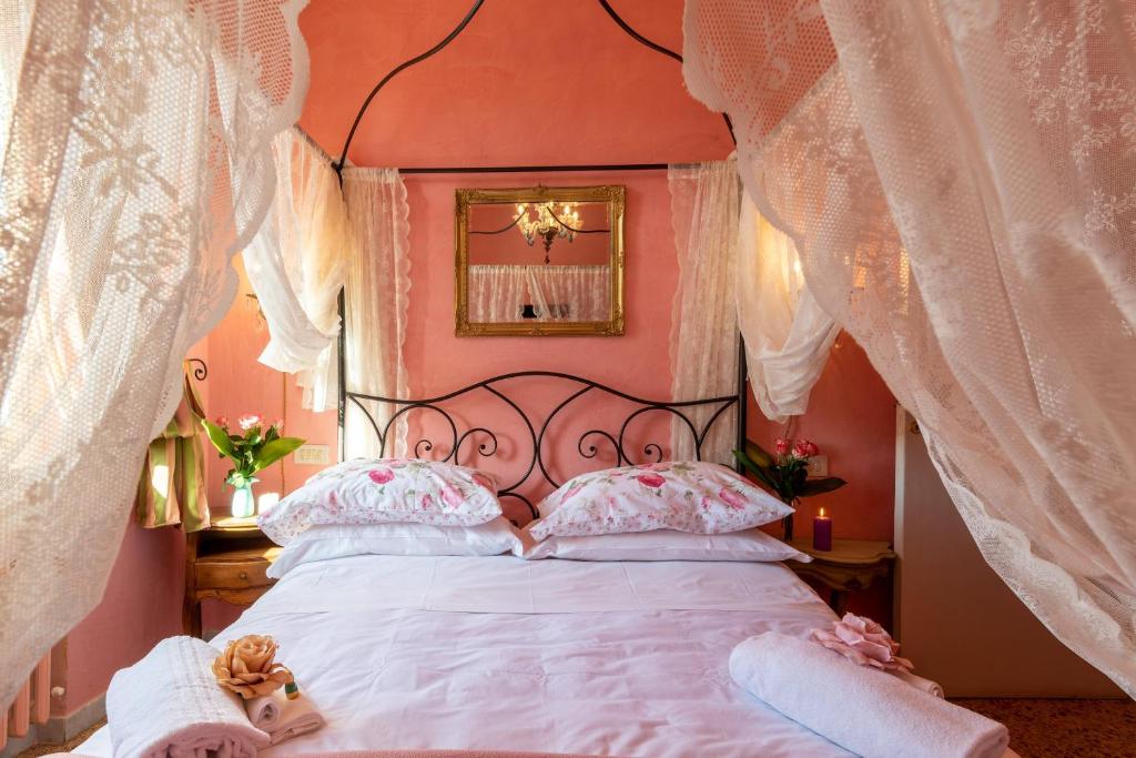 um quarto com uma cama com paredes e cortinas cor-de-rosa em BIBI BOUTIQUE AREZZO Appartamento Rosafragola - Verdeconiglio em Arezzo