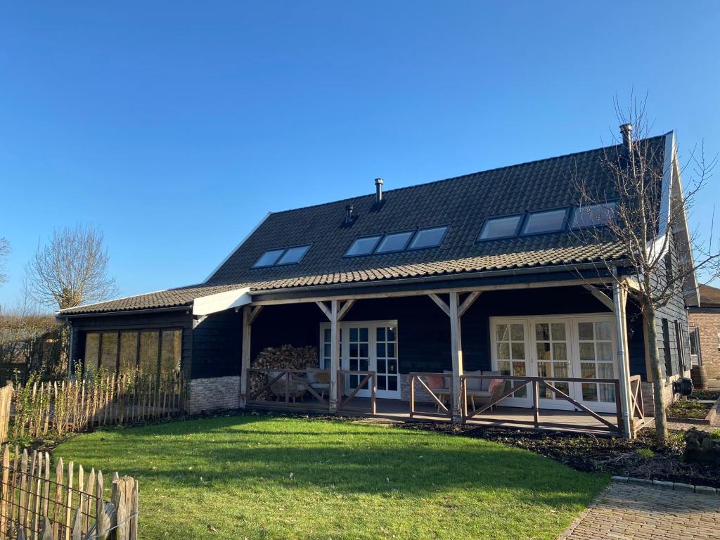 uma casa com um telhado preto e um quintal em De Porrel Polsbroek Unit met Privé Jacuzzi, Spa en Sauna em Polsbroek