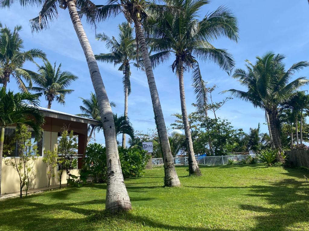 a group of palm trees in front of a house at Kesa Cloud 9 Hotel & Resort Siargao in General Luna