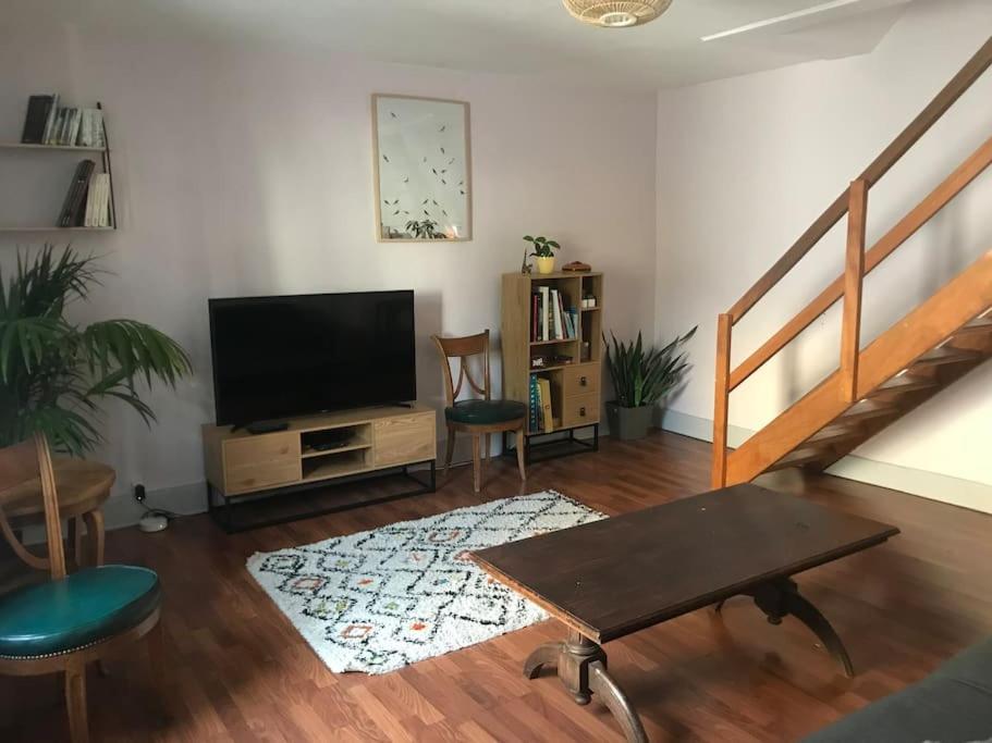 een woonkamer met een flatscreen-tv en een tafel bij Charmant appartement au calme avec parking in Besançon