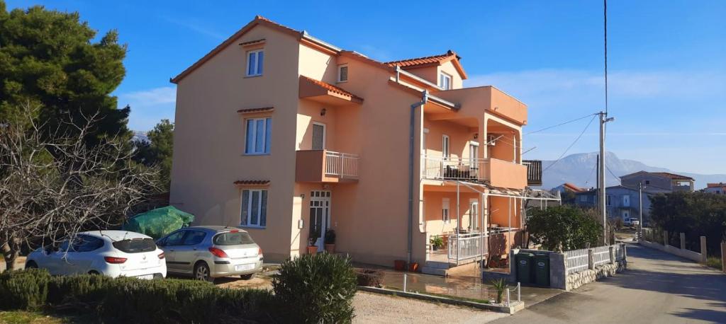 a house with two cars parked in front of it at Apartman Anita in Kaštela