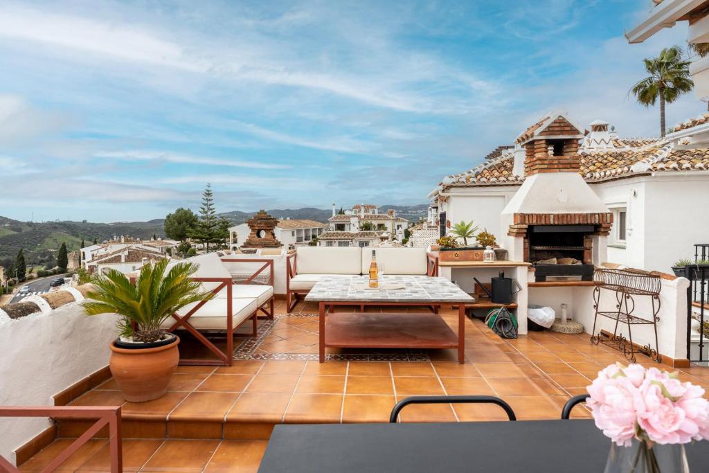 a patio with a table and a fireplace on a roof at MalagaSuite Mijas Golf Panoramic Views in Mijas Costa