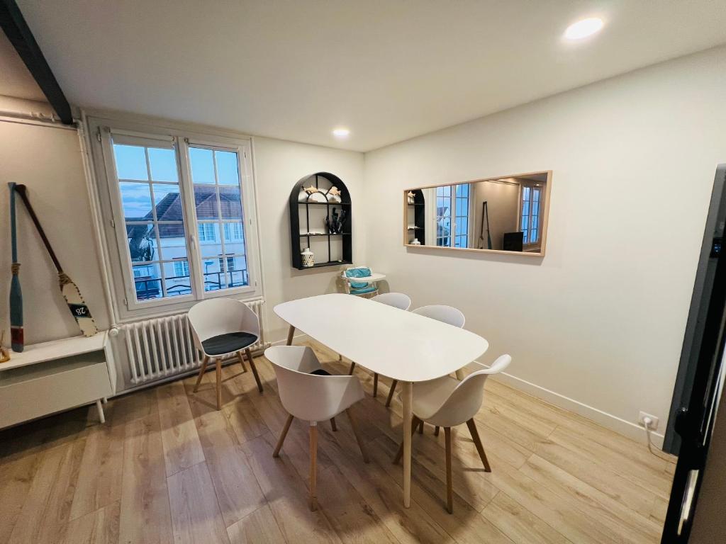 une salle à manger avec une table et des chaises blanches dans l'établissement Bel appartement plein centre 100m de la mer, à Merville-Franceville-Plage