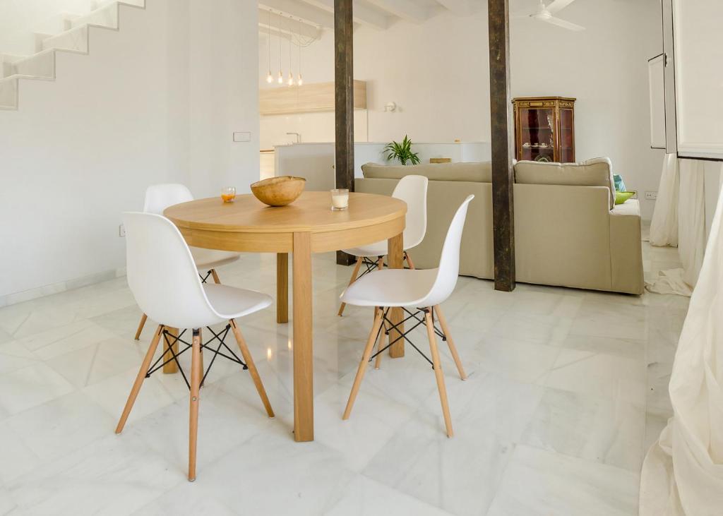 een eetkamer met een houten tafel en witte stoelen bij El Erizo Apartamentos in Tarifa