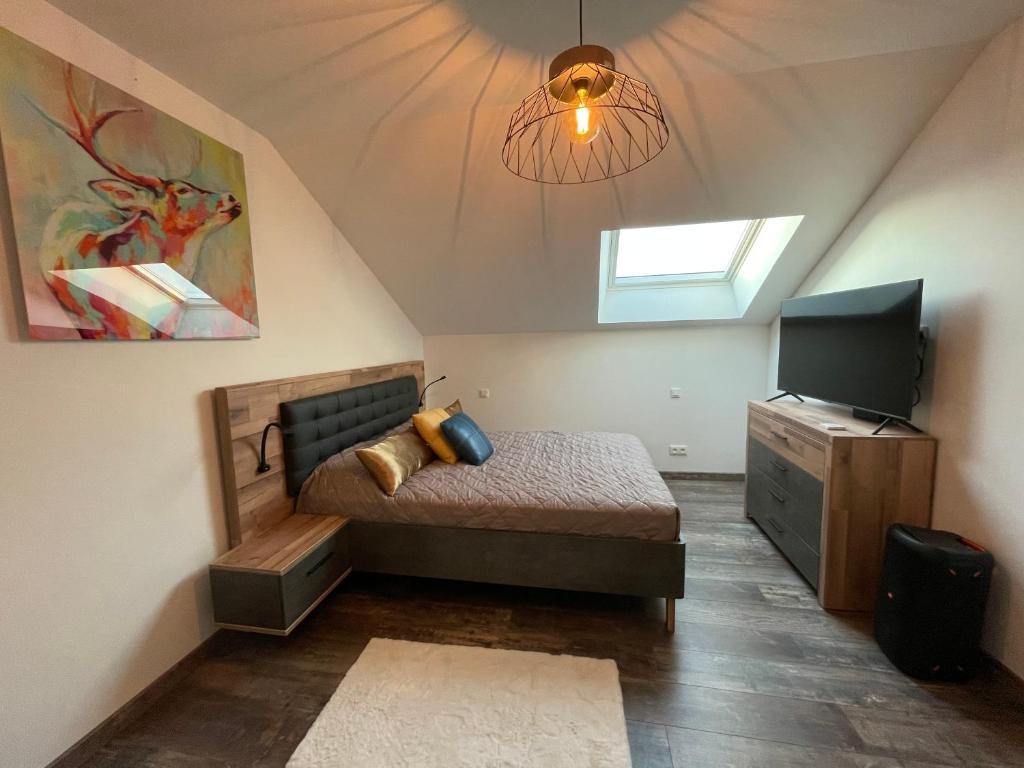um quarto no sótão com uma cama e uma televisão em Nuits en Sologne em Romorantin-Lanthenay