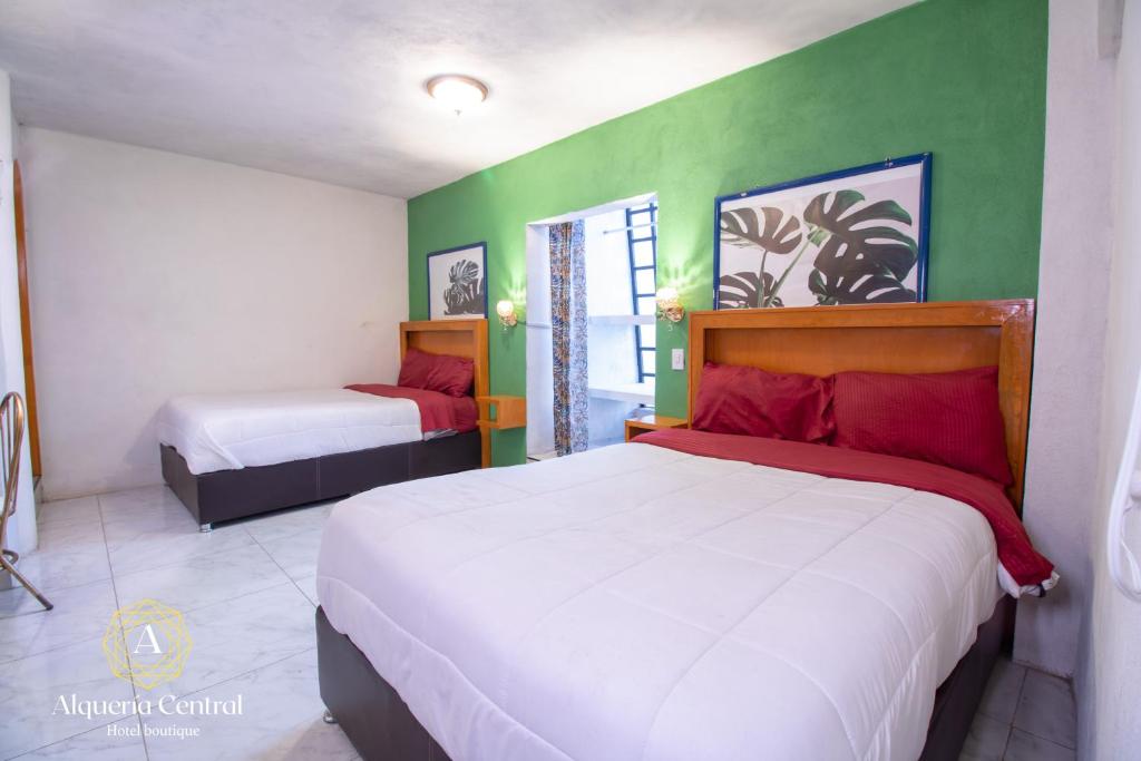 a bedroom with two beds and a green wall at Alquería Central hotel in Tlaxco de Morelos