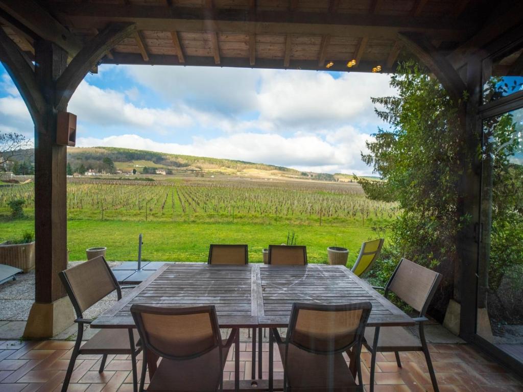 a table and chairs on a patio with a view of a field at By les Climats - Gîte du Tacot - Gevrey-Chambertin in Gevrey-Chambertin