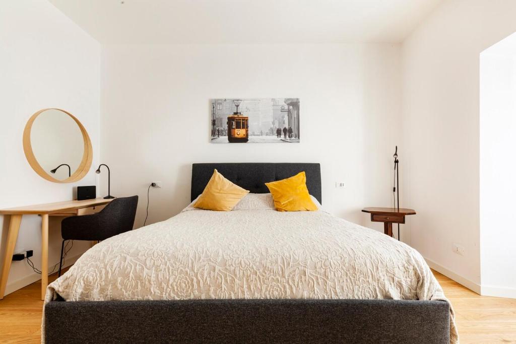 ein Schlafzimmer mit einem Bett mit gelben Kissen und einem Spiegel in der Unterkunft Splendido bilocale in vecchia Milano in Mailand